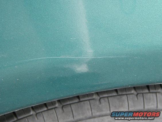 A view over the rear driver side wheel well after an apparent "keying" by antisocial elements.