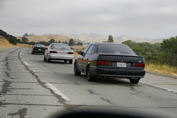 Black Ford Taurus with a spoiler and California license plate 5YRW393 driving on a highway