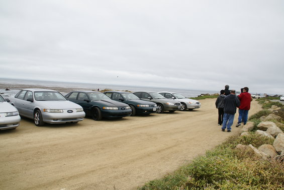 Silver 1996 Ford Taurus parked on dirt road, ocean in background