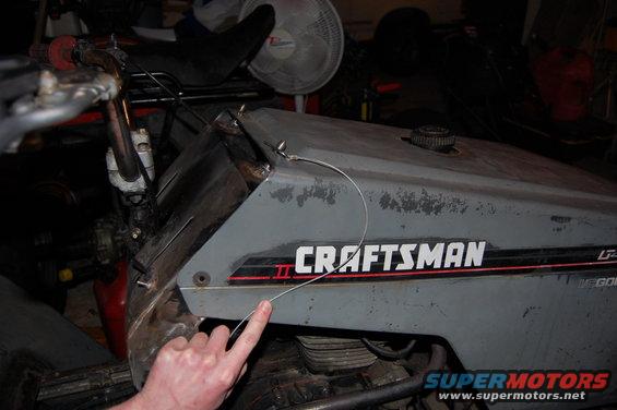 Close-up of a Craftsman riding mower's body panel with a finger pointing to a wire