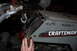 2010 Kawasaki BAYOU 220 - A hand is shown near the cable mechanism on the gray body of a Craftsman II riding mower.