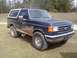 1990 Ford Bronco - This Ford Bronco is shown from the front-three-quarter angle, appearing muddy after off-road use.