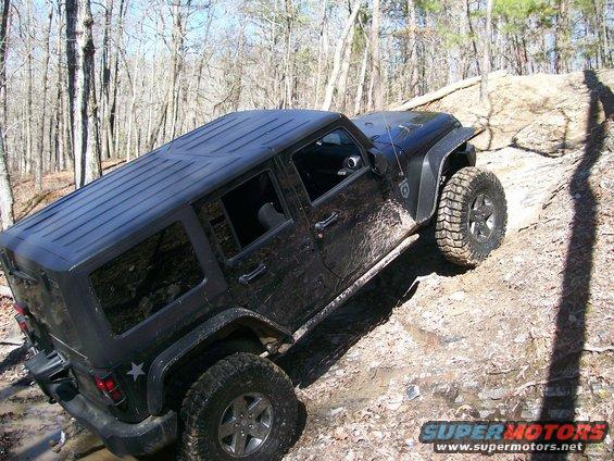 Black 2007 Jeep Wrangler on a muddy, wooded trail