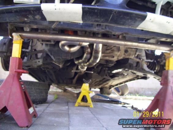 Custom exhaust headers on a car's underbody, supported by jack stands
