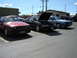 1983 Mercury Capri - Three Fox body cars are parked in a lot on a sunny day. The red car in front has a license plate that reads 2.AXB03.
