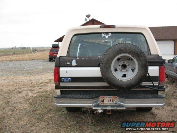 1992 Ford Bronco rear view with spare tire mounted on back. Another SUV is parked in the background