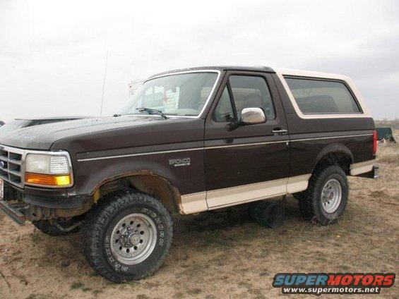 Brown 1992 Ford Bronco with a tan top, parked on dirt