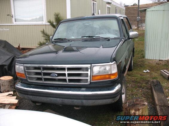 Front view of a dark green 1995 Ford Bronco parked outside a mobile home