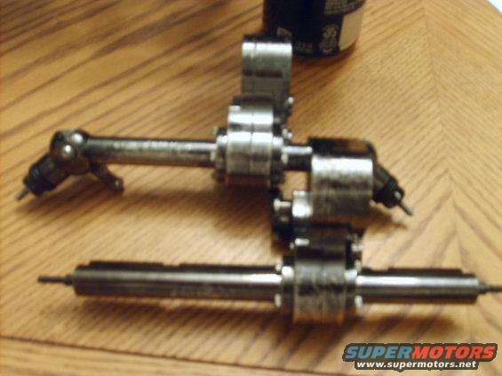 Two metal fuel injectors with black connectors on a wooden surface