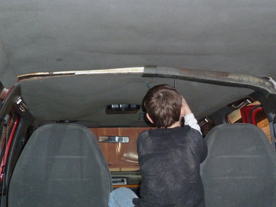 Interior view of a vehicle with a person working on the headliner
