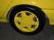 2002 Ford Taurus - Close-up of a yellow car's wheel and tire, showing the five-spoke rim design.