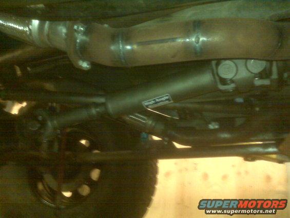 Driveshaft with "High Performance" sticker and exhaust pipe under a vehicle