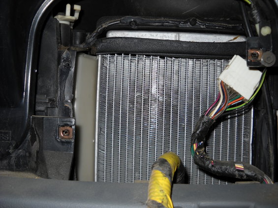 Heater core with visible fins and a black wiring harness with multiple colored wires connected to a white connector
