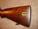 2003 Ford Crown Victoria - Close-up of a wooden rifle stock showing wear and yellow markings.