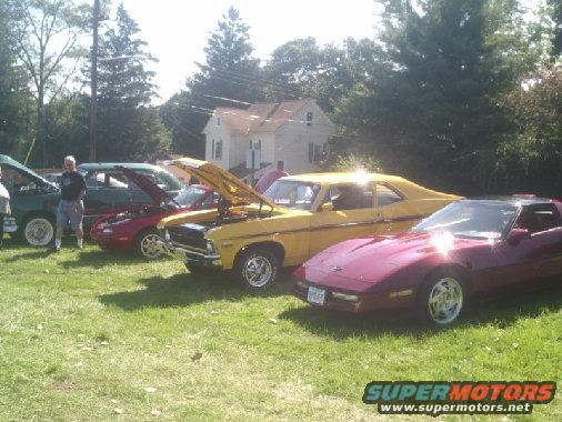 Yellow 1970s coupe and maroon sports car parked on grass with hoods up