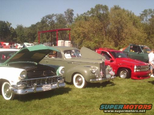 Green and white classic car front view, hood open. Appears to be a 1955 Ford Fairlane