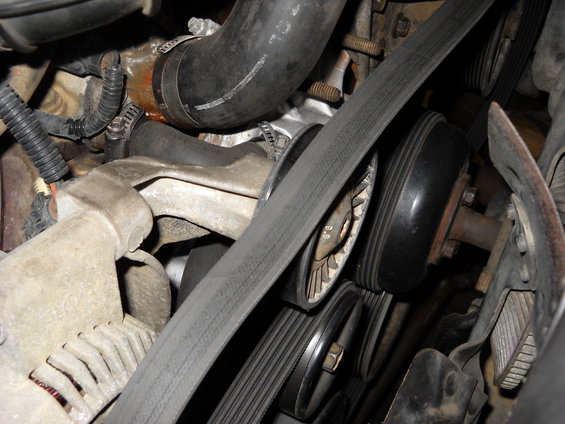 Engine belt system with multiple pulleys and a ribbed belt