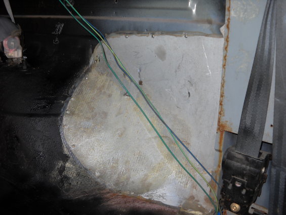 Close-up of a vehicle's interior panel with exposed wires and some rust