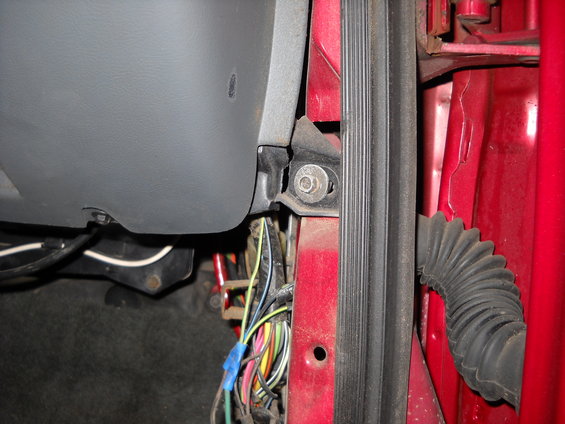 Close-up of red vehicle interior door jamb with exposed wiring harness and gray plastic trim