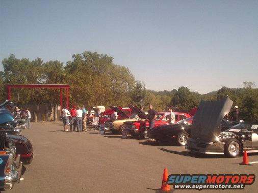 Cars lined up with hoods open at an outdoor car show