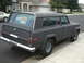 1977 Jeep Cherokee - A dark gray Jeep Wagoneer is parked on the side of a street with a 'For Sale' sign visible in the back window.