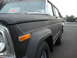 1977 Jeep Cherokee - A black Jeep Wagoneer is parked on a street with a 'For Sale' sign visible in the window.