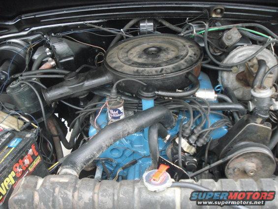 Engine bay with blue engine block, black air cleaner, and battery. Visible text includes 'EverStart' and 'SUPERMOTORS'