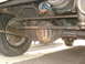 1977 Jeep Cherokee - Close-up of the undercarriage, focusing on the drivetrain and suspension components of an older vehicle.
