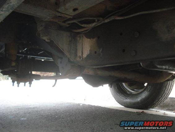 Underside view of vehicle frame and suspension, showing leaf springs and tire