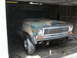 1977 Jeep Cherokee - A camouflage-painted Jeep Wagoneer sits in a garage, appearing to be undergoing some work.