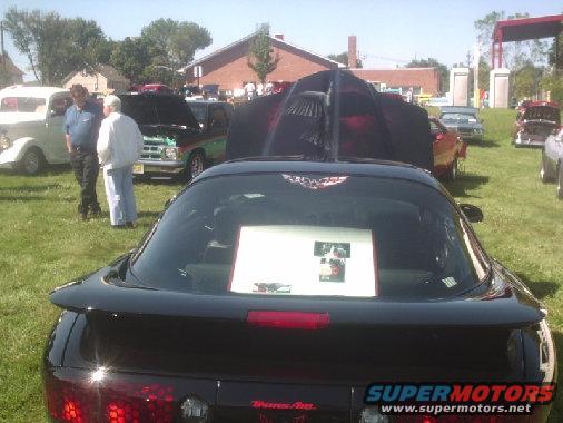 Black car with spoiler and red taillights, seen from rear