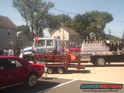 Fire truck with 'Big Dog Towing' on side, pulling a trailer with trophies and a small wagon