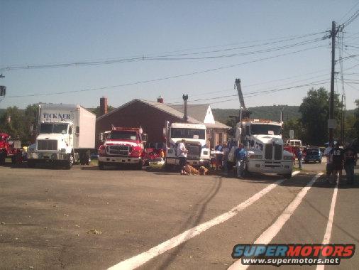 Several trucks parked in a lot with people around them
