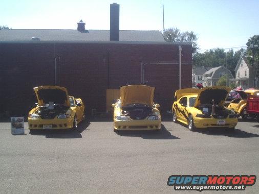 Three yellow Ford Mustangs from the late 1990s with hoods open