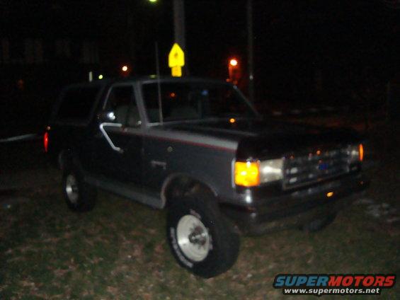 Dark colored Ford Bronco parked at night. It's a 1991 model
