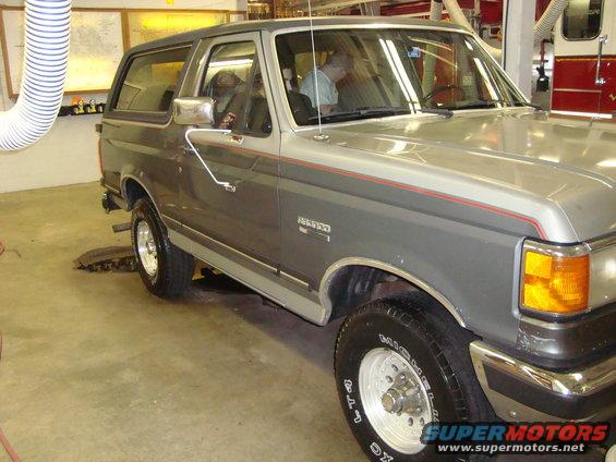 Gray and silver two-tone Ford Bronco with red pinstripes, seen from the front three-quarter angle