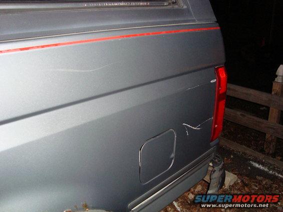 Gray SUV rear quarter panel with red pinstriping and scratches