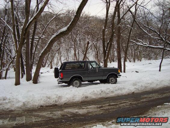 1991 Ford Bronco parked on a snowy road with trees in the background