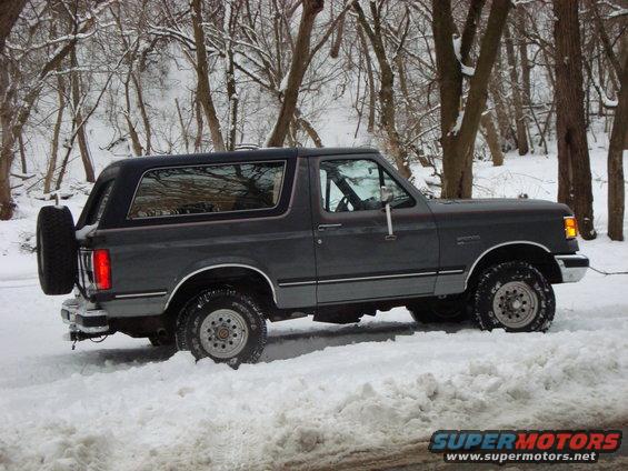 Gray Ford Bronco with spare tire on back driving in snow