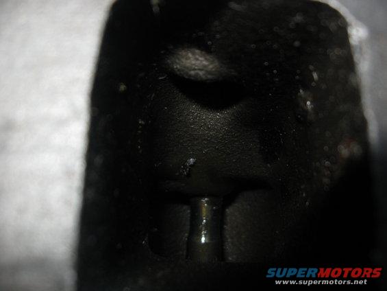 Black engine part with a metal pin protruding from a dark recess