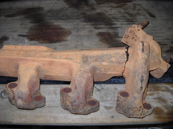 Rusty, cracked exhaust manifold with three visible ports