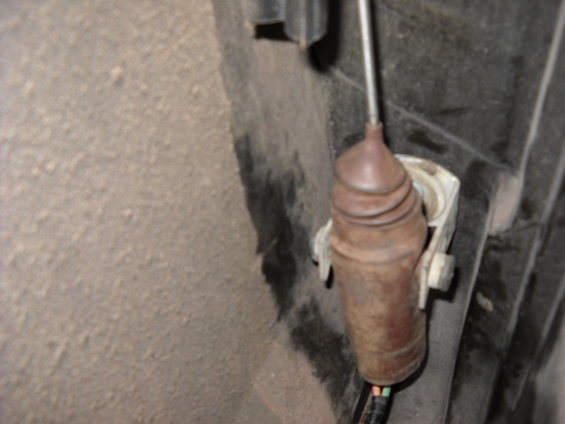 Rusty door lock actuator with wiring attached, mounted to a textured surface