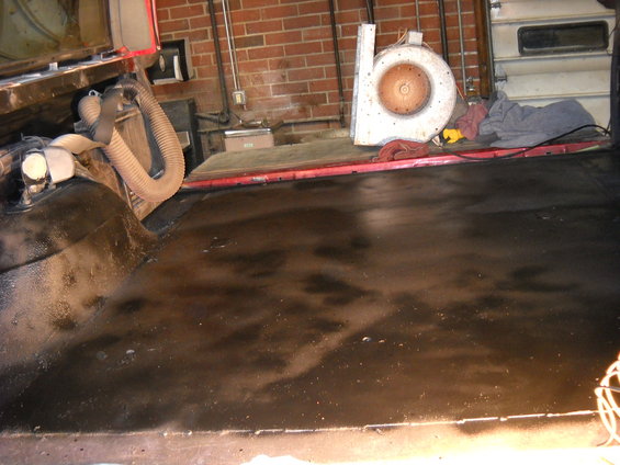 View of the dark, possibly wet, floor inside a vehicle, with some hoses and equipment visible