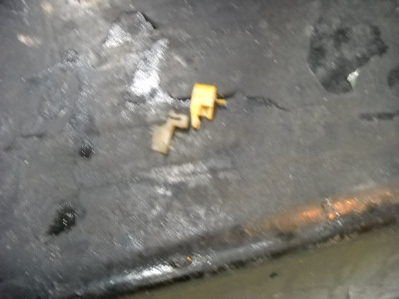 Two small plastic door lock actuators, one tan and one yellow, on a dark, textured surface