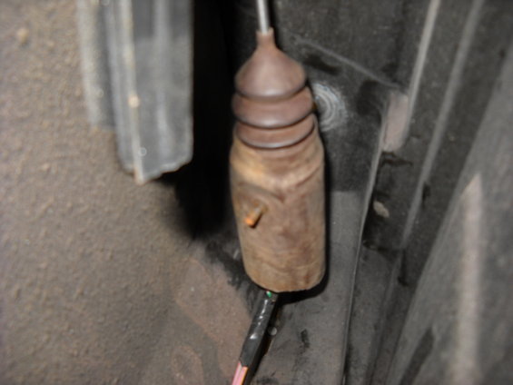 close-up of a rusty door lock actuator rod with a rubber boot