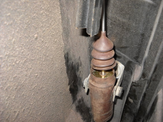 close-up of a rusty door lock actuator rod with a rubber boot