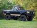 1990 Ford Bronco - A lifted 1990 Ford Bronco sits on a grassy field with trees in the background.