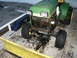 1966 Ford Bronco - A green and yellow John Deere tractor is equipped with a snow plow and chains on its rear tires.