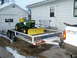 1966 Ford Bronco - A green and yellow tractor with a snow plow is loaded onto a trailer in front of a white house and garage.