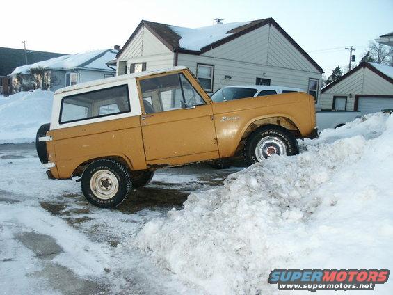 Yellow 1966 Ford Bronco with white top stuck in a snowbank